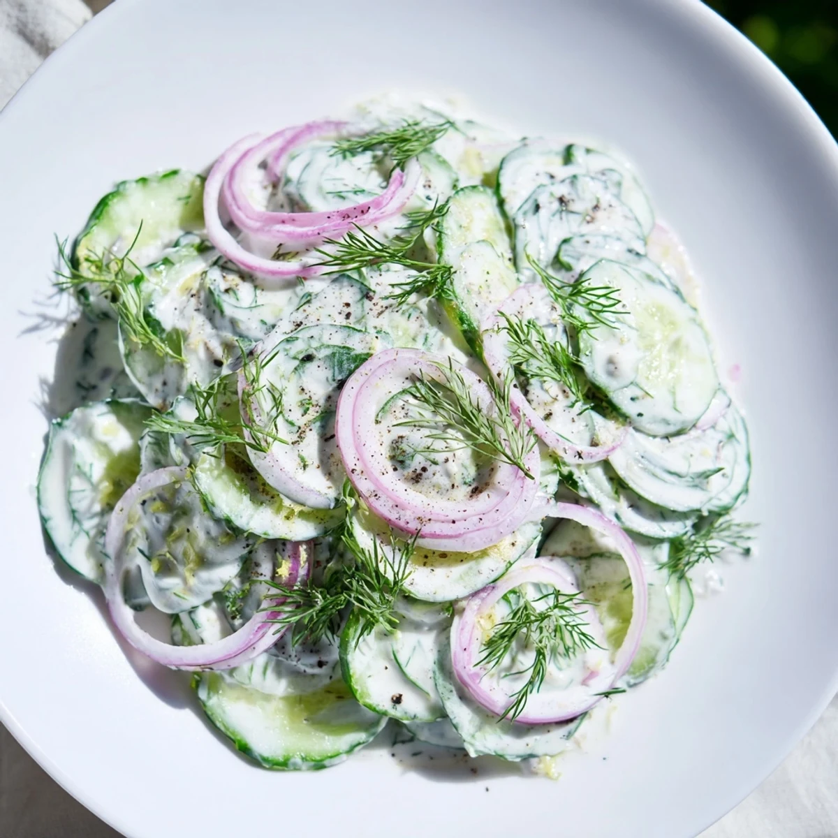 Erfrischender kalter Gurken-Dill-Salat mit cremiger Jogurt-Kräuter-Soße, garniert mit frischem Dill.