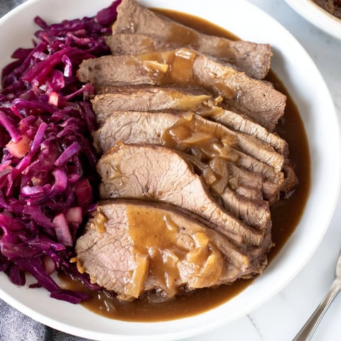 Saftiger Sauerbraten mit zartem Rindfleisch und würzigem Apfelrotkohl serviert  