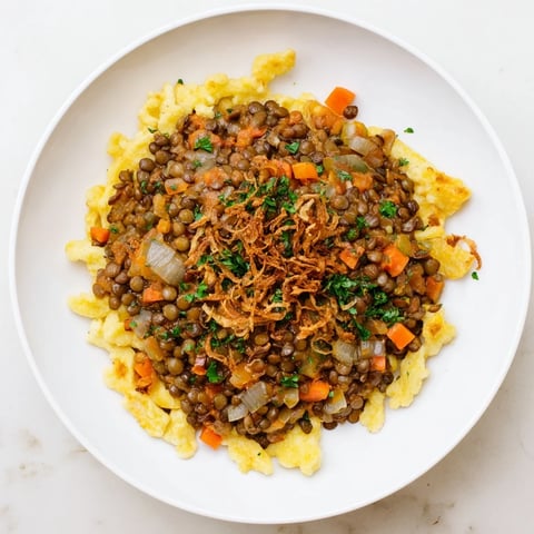 Budget Lentil & Spätzle Bowl: A steaming bowl showing flavorful lentils and golden spätzle with fresh parsley.