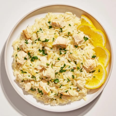 A close-up of finished Creamy Lemon Chicken Orzo, garnished with fresh parsley and lemon slices.