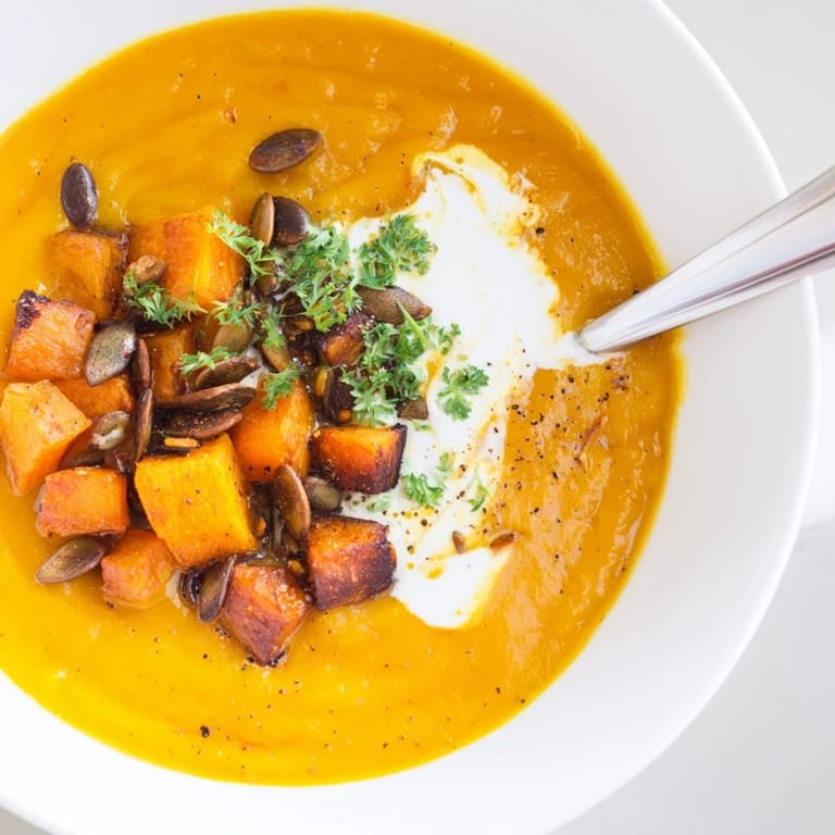 Wärmende, samtige Kürbissuppe mit geröstetem Gemüse und einem Hauch von Sahne.  