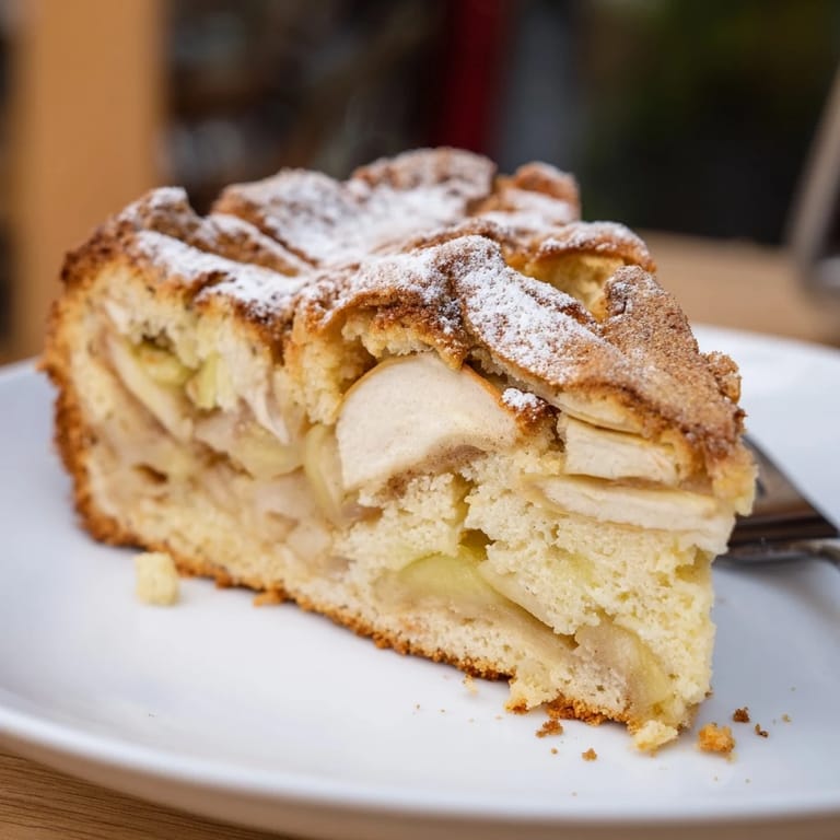 Zarte Stücke von deutschem Apfelkuchen, garniert mit Puderzucker und warm serviert.